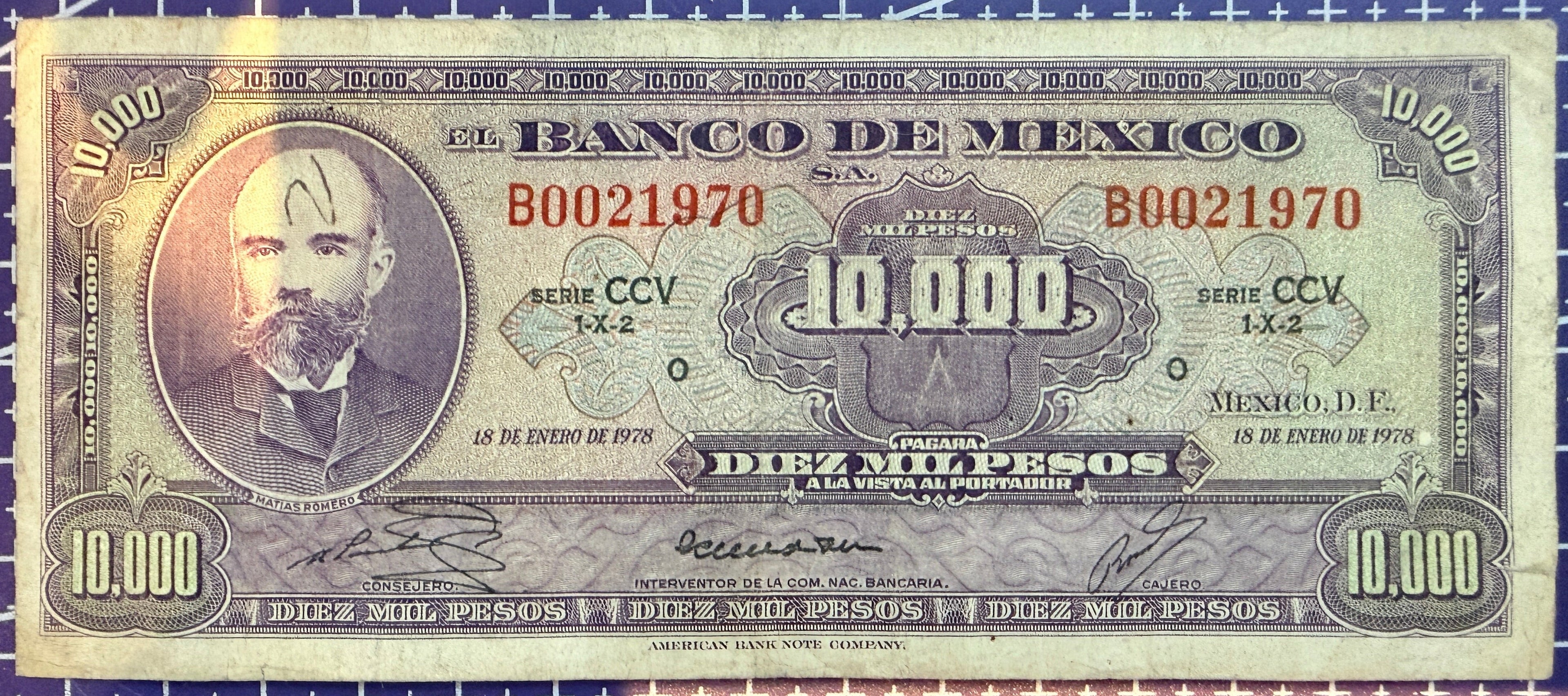10000 peso bill on a blue grid background
